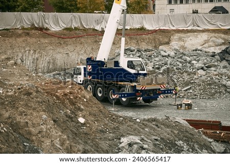 Modern Construction Machinery in Action. View of the mobile crane with a truck. Cable-controlled crane on a truck-type carrier and as self-propelled. Construction site in Europe. Royalty-Free Stock Photo #2406565417