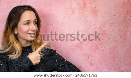 Cheerful woman pointing at pink textured background. Banner with copy space for text.