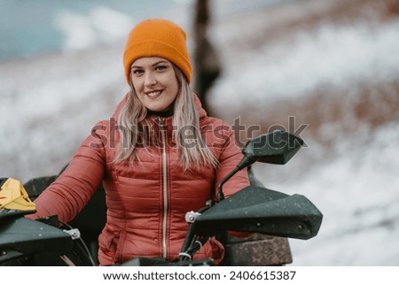 A beautiful blonde woman enjoys the winter wonderland, delighting in a thrilling quad ride through the snow-covered landscape, radiating joy and exhilaration in the midst of the wintry adventure