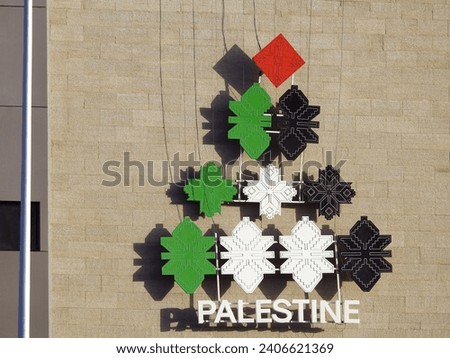 A pyramidal shape with the colors of the Palestinian flag, with the word Palestine below it, An Icon on a building in Egypt for the state of Palestine as a solidarity with the Palestinian people