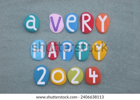 A very happy 2024 composed with hand painted multi colored stone letters and numbers over green sand Royalty-Free Stock Photo #2406638113