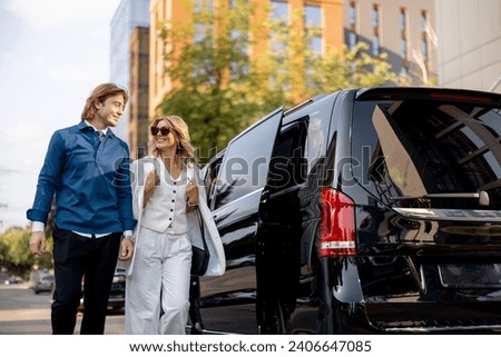 Business people get out of a minivan taxi, during a business trip by car. Concept of business trips and transportation Royalty-Free Stock Photo #2406647085