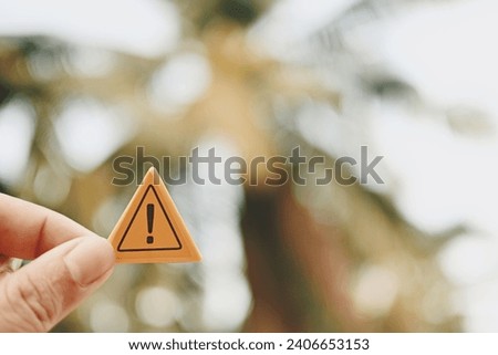 hand holding caution sign, green nature copy space background for text, planning and manage to success business concept