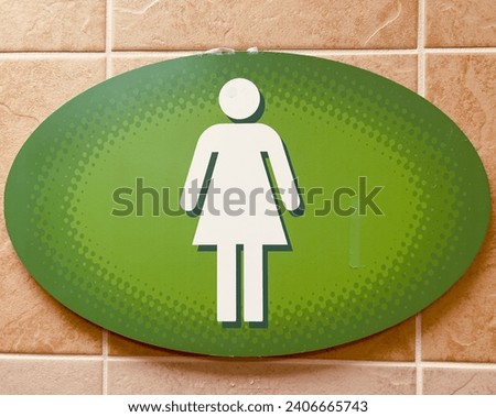 Toilet sign woman green white color on tiles wall.