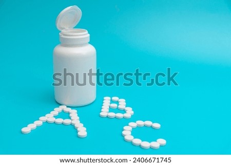 White tablets near the pharmacy jar in the shape of the letters ABC. The concept of vitamins.