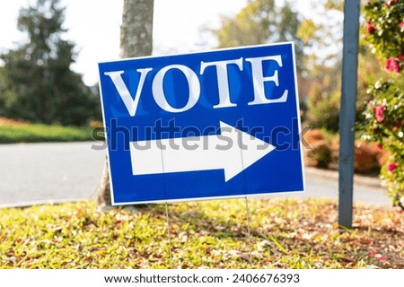 A Blue 'Vote' Sign with Arrow on a Sunny Day, Pointing the Way to a Polling Station.