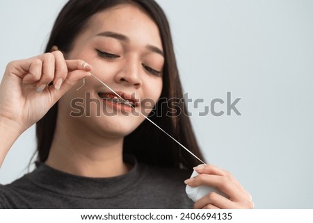 Asian woman braces using dental floss. Teeth braces on the white teeth of women to equalize the teeth. Bracket system in smiling mouth, close up photo teeth, macro shot, dentist health concept. Royalty-Free Stock Photo #2406694135
