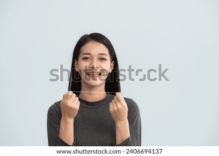 Asian woman braces using dental floss. Teeth braces on the white teeth of women to equalize the teeth. Bracket system in smiling mouth, close up photo teeth, macro shot, dentist health concept. Royalty-Free Stock Photo #2406694137