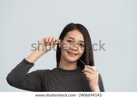Asian woman braces using dental floss. Teeth braces on the white teeth of women to equalize the teeth. Bracket system in smiling mouth, close up photo teeth, macro shot, dentist health concept. Royalty-Free Stock Photo #2406694143