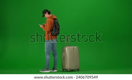 Portrait of person tourist isolated on chroma key green screen background. Young woman with suitcase holding smartphone looking at the information online.