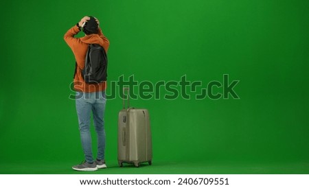 Portrait of person tourist isolated on chroma key green screen background. Young man looking at the departure board, late to flight, upset expression.