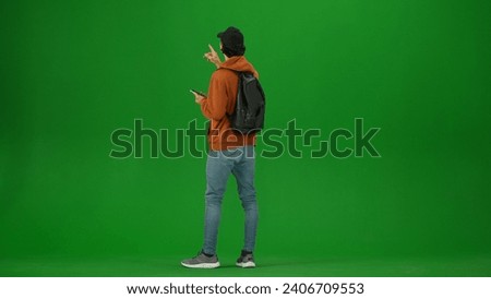 Portrait of person tourist isolated on chroma key green screen background. Young woman holding smartphone looking at the information board.
