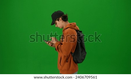 Portrait of person tourist isolated on chroma key green screen background. Close up shot young man holding smartphone and looking for departure information.