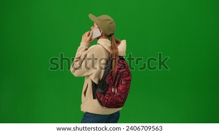 Portrait of person tourist isolated on chroma key green screen background. Close up shot young woman talking on smartphone looking at the departure board.