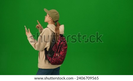 Portrait of person tourist isolated on chroma key green screen background. Close up shot young woman holding smartphone and looking at the departure board.