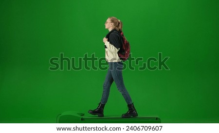 Portrait of person tourist isolated on chroma key green screen background. Young woman in glasses and casual clothing walking and looking around.