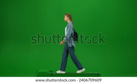 Portrait of person tourist isolated on chroma key green screen background. Young woman with small bag in casual clothing walking and looking around.
