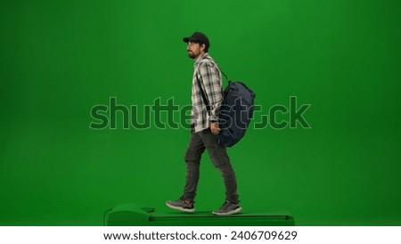 Portrait of person tourist isolated on chroma key green screen background. Adult man in cap with sport bag walking and looking around.
