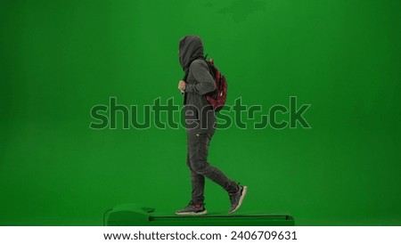 Portrait of person tourist isolated on chroma key green screen background. Adult man in hood on with backpack walking and looking away from camera.