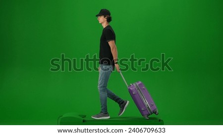 Portrait of person tourist isolated on chroma key green screen background. Young man in cap with suitcase walking and looking around.