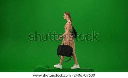 Portrait of person tourist isolated on chroma key green screen background. Young woman with laptop bag in dress walking and looking around.