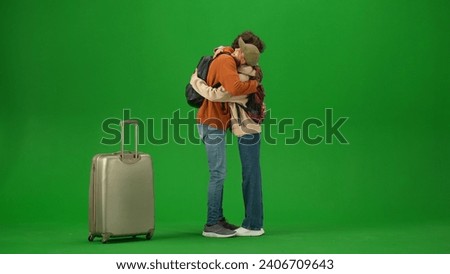 Portrait of person tourist isolated on chroma key green screen background. Young couple meets at the arrival area, man and girl hugging happy expression.