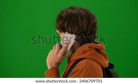 Portrait of person tourist isolated on chroma key green screen background. Close up shot young man talking on smartphone looking away.