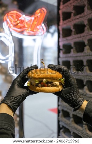 
Holding a hamburger in his hands. Delicious appetizing burger.Fast food cafe.American food. Burger recipe.Cafe menu.Appetizing food.Home delivery of food.