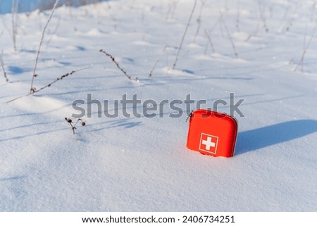First aid kit lies in the snow in nature, cold season, red bag with medicines, white cross on the box with medicines, winter trekking in the snow. High quality photo