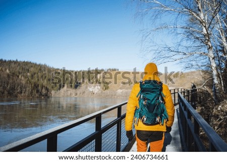 Man with backpack going into the distance, view from the back of a tourist backpack, trekking in the mountains, cold season, sunny day for nature walks. High quality photo