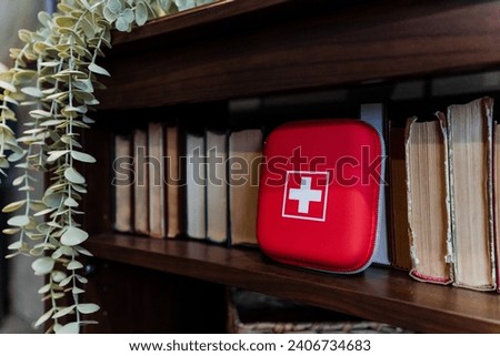Home first aid kit stands among books, health care concept. High quality photo