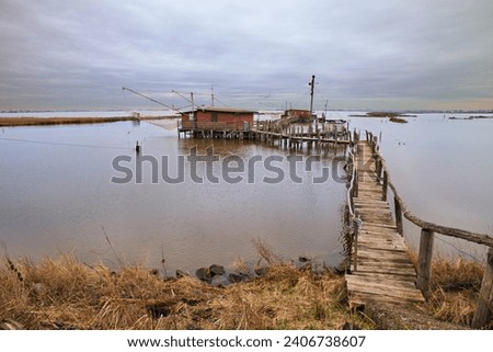 Comacchio, Ferrara, Emilia Romagna, Italy: landscape of the wetland in the nature reserve Po Delta Park with fishing huts in the lagoon 

