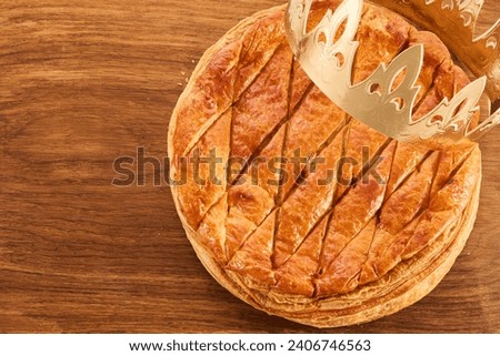 Epiphany cake on wooden table. Galette des rois traditional Epiphany cake in France Royalty-Free Stock Photo #2406746563