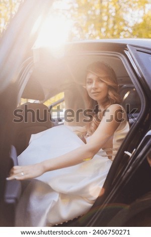A bride takes pictures in the black car
