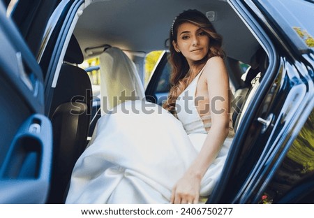 A bride takes pictures in the black car