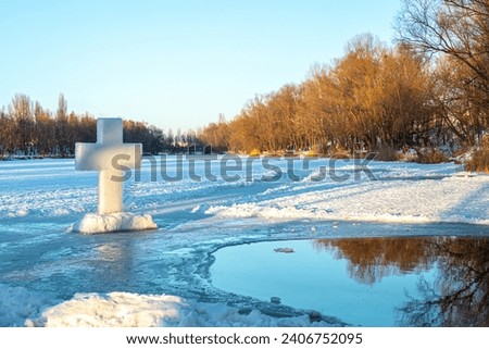frozen hollowed ice-hole serves as a venue for the immersion of believers in a religious rite, marking the Epiphany with icy waters and a towering cross. Royalty-Free Stock Photo #2406752095