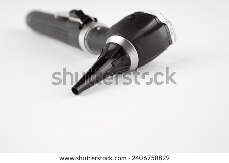 A black otoscope isolated on a white background. A medical device used by doctors to look into the ear canal of a patient during a regular check-up or a physical exam to investigate ear symptoms. Royalty-Free Stock Photo #2406758829
