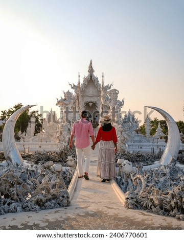 White Temple Chiang Rai Thailand,a diverse couple of men and women visit Wat Rong Khun temple at sunset, Northern Thailand. Royalty-Free Stock Photo #2406770601
