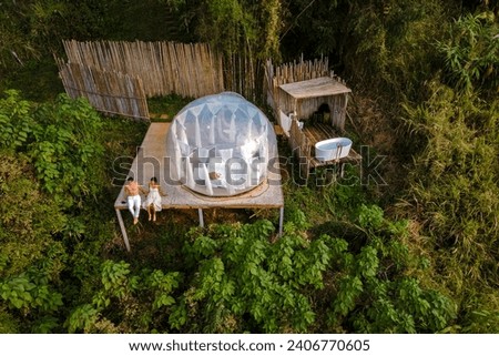 couple man and women in a bubble tent with an outdoor bathroom with a bath in the jungle rainforest. Luxury glamping 
