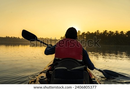 Kayaking on the river during sunrise, young man canoeing in Kavvayi Island Kannur, Kerala backwaters adventure activities  Royalty-Free Stock Photo #2406805377