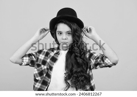 Child girl in magician hat, cylinder hat isolated on yellow background. Headwear. Clothes accessories. Fashion headwear for gentlemen in vintage style, old classic cylinder. Royalty-Free Stock Photo #2406812267