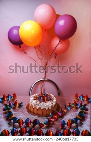 A delicious cream cake with birthday candles and balloons. Table setup festive mood party. The pink color imbues you with tenderness and a sense of celebration.