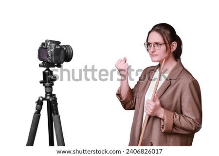 Angry woman teacher with camera on tripod leads online school on isolated on a white background, copy space Royalty-Free Stock Photo #2406826017