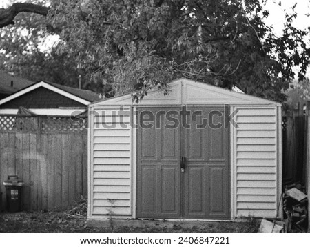 Picture of a black and white vintage like garage in the backyard.