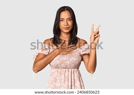 Young Filipina with long black hair in studio taking an oath, putting hand on chest.