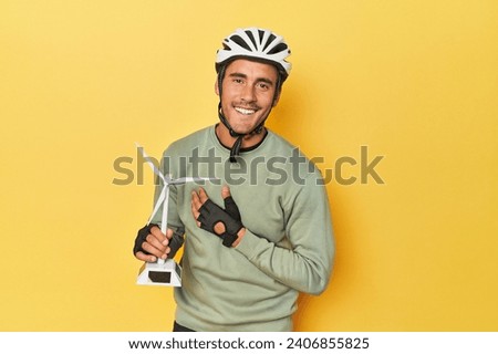 Cyclist with windmill, clean transport theme laughs out loudly keeping hand on chest.