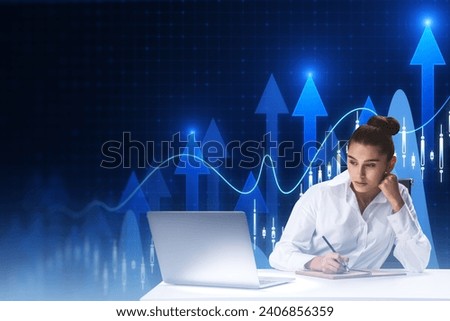 Attractive young european businesswoman working at desk with laptop, paperwork and growing forex chart with bright upward arrow on blurry pixel background. Success, financial growth and trade concept