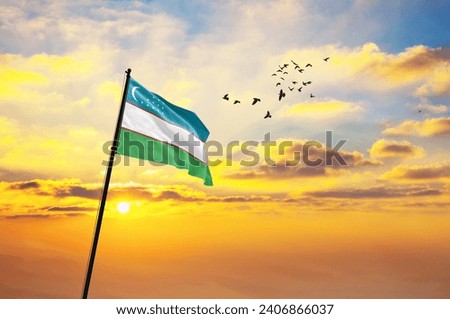 Waving flag of Uzbekistan against the background of a sunset or sunrise. Uzbekistan flag for Independence Day. The symbol of the state on wavy fabric. Royalty-Free Stock Photo #2406866037