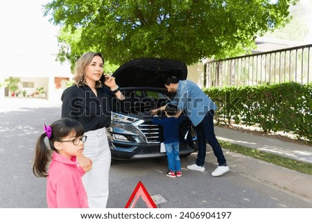 Caucasian parents with their children having mechanical problems with a broken down car and calling for help on the road