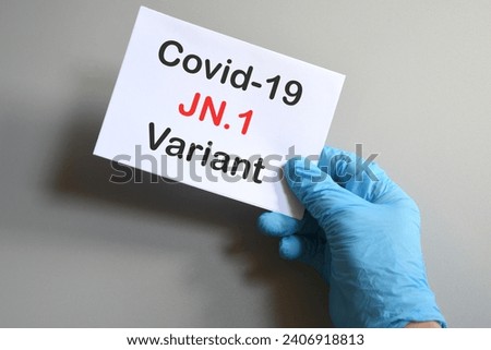 The hands of doctor in blue gloves with white paper and text "Covid-19 JN.1 Variant". Concept for the new variant of SARS-CoV-2 JN.1 Covid-19. Royalty-Free Stock Photo #2406918813